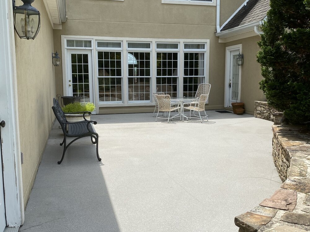 Same concrete patio clean and light gray after pressure washing