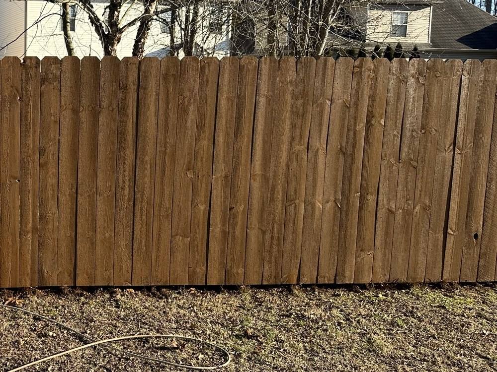 Same wood privacy fence restored to a warm brown color after staining