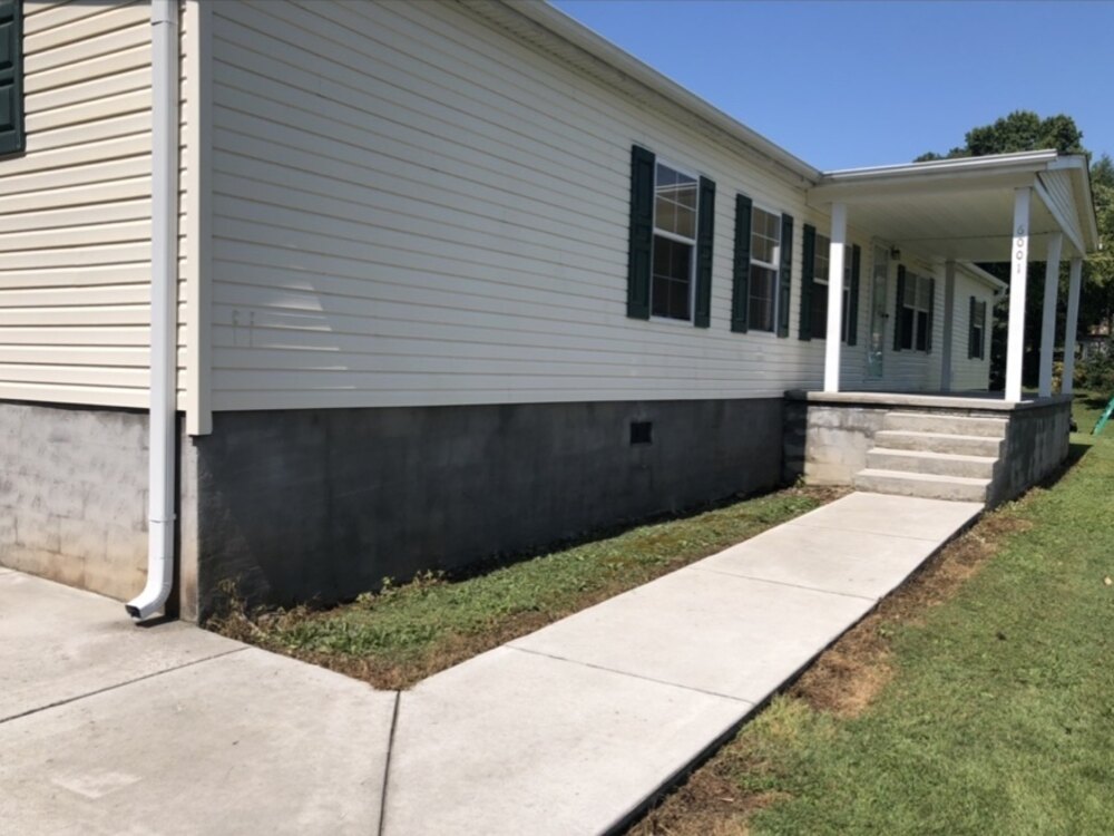 Dark algae and mildew staining on a home's foundation and siding before house washing